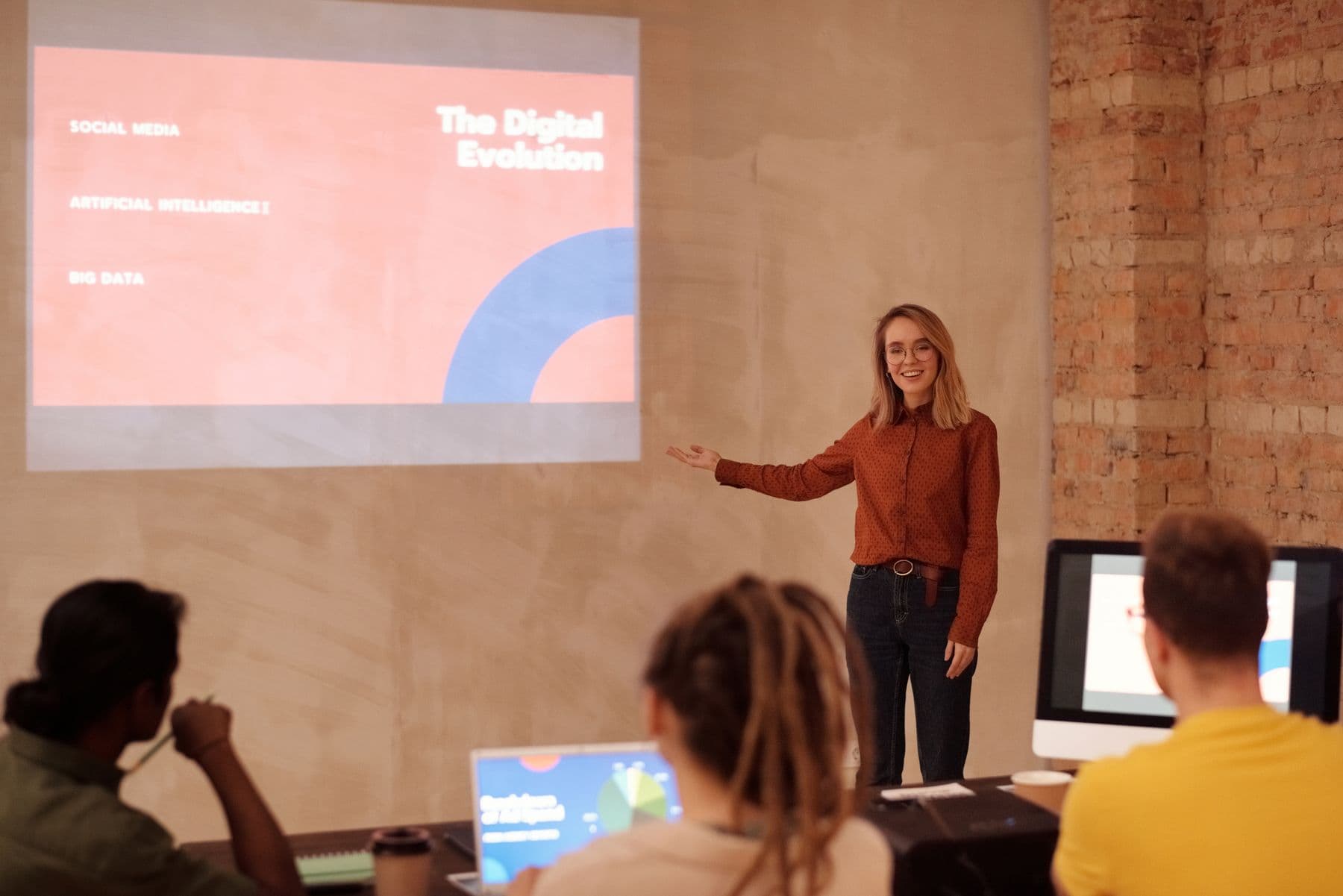 Presenter explains a topic on artificial intelligence and big data to a small audience in front of a projection screen