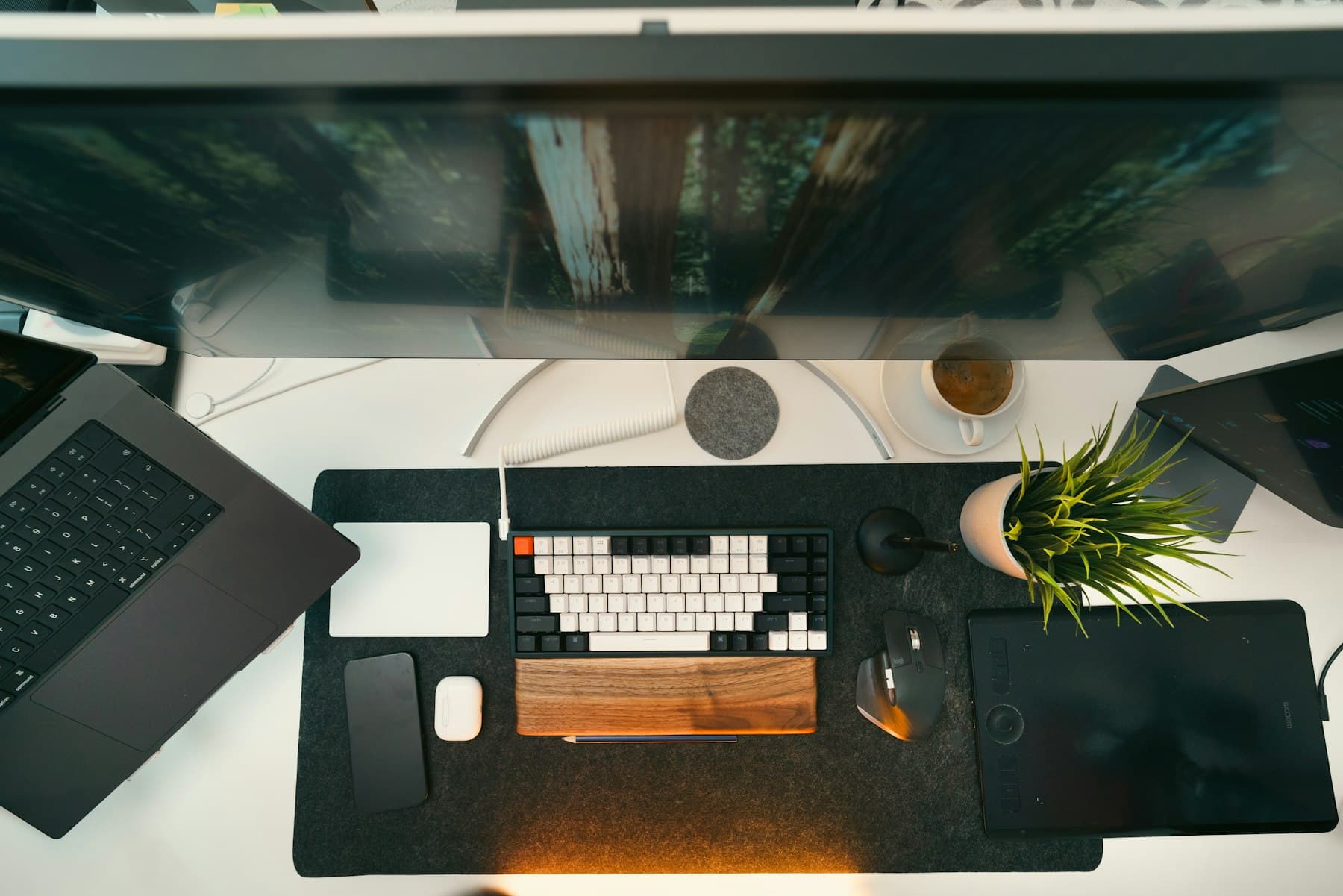 Aufgeräumter Schreibtisch von oben mit mechanischer Tastatur, Holz-Handballenauflage, Pflanze, Kaffee und Laptop