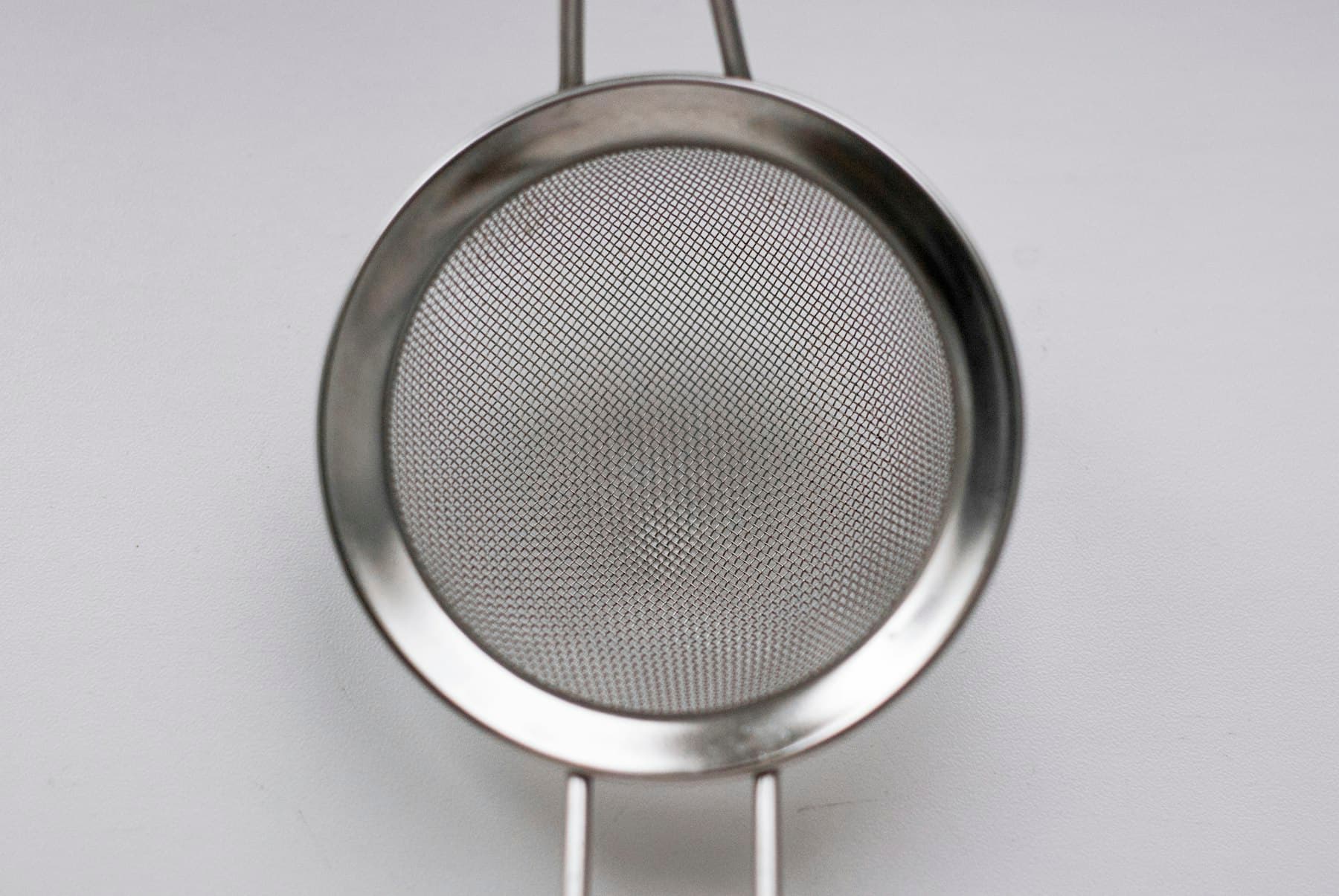 A fine stainless steel sieve against a neutral background, symbolizing the filtering and cleaning of data