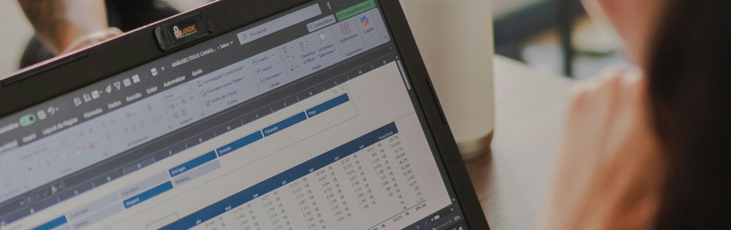 Close-up of a laptop screen showing the Excel ribbon and a color-formatted spreadsheet with sales figures