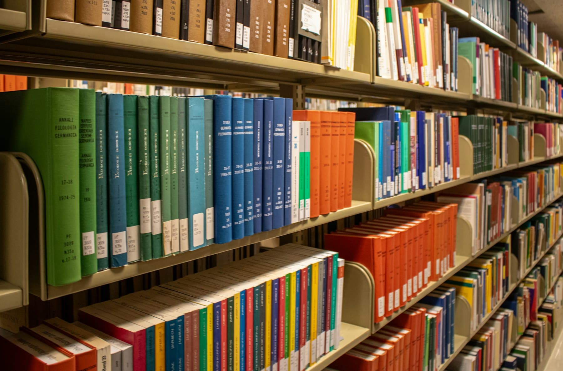 View down a library aisle lined with densely packed shelves of colorful book spines