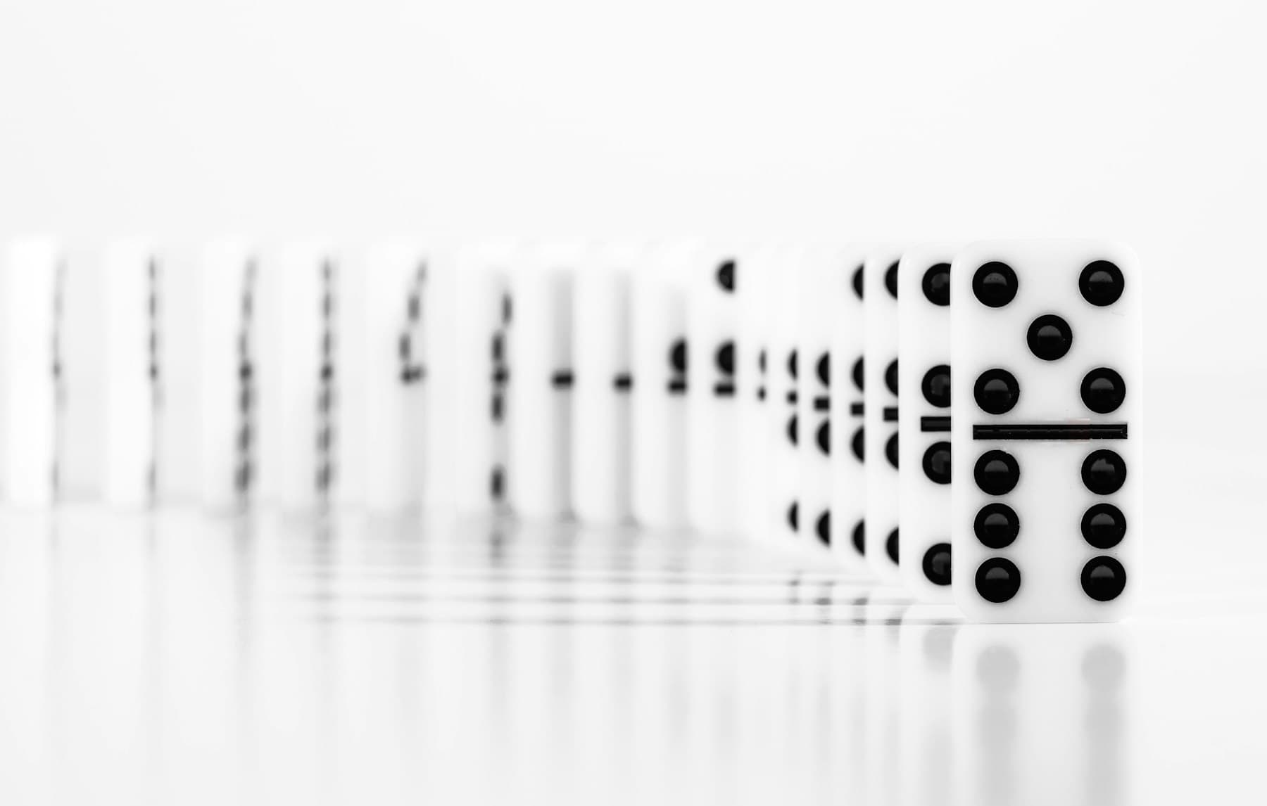 A row of standing dominoes about to trigger a chain reaction, symbolizing an automated sequence of process steps