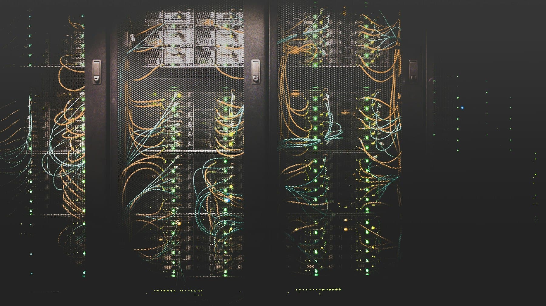 Row of three server racks with structured cabling and blinking status LEDs in a data center