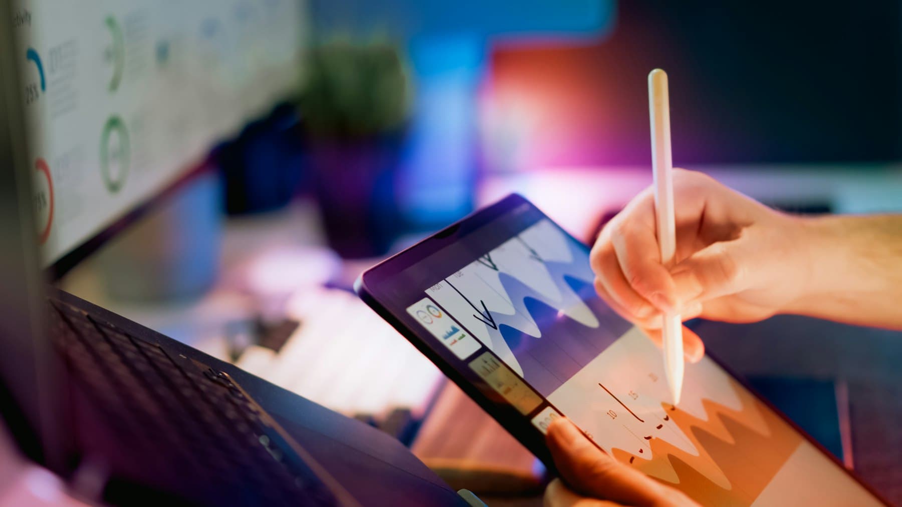 Close-up of a hand using a stylus to review data on a tablet displaying charts