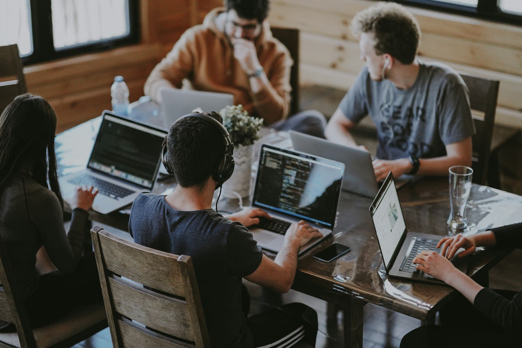 Several people work with their own laptops at a shared table