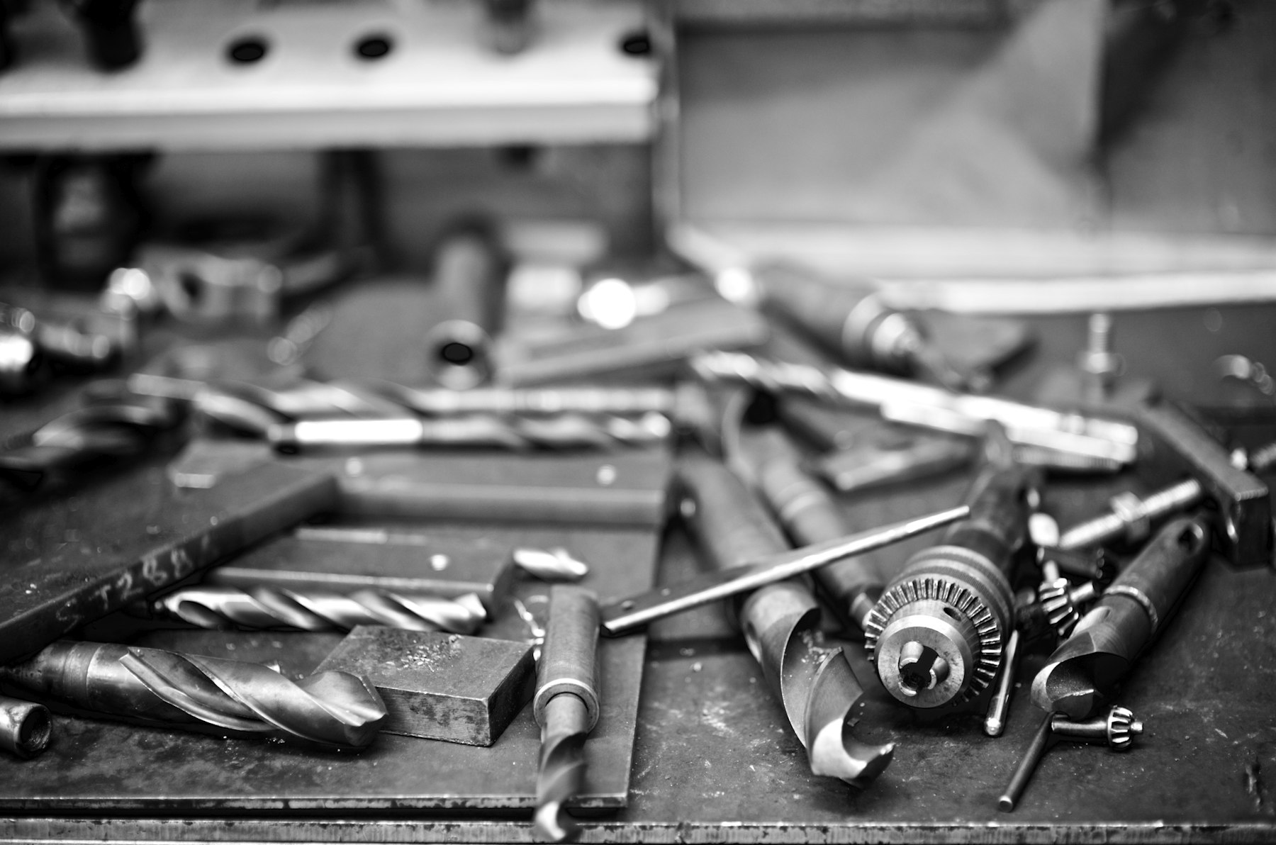 Assorted drill bits and tools scattered on a workbench, black and white photograph